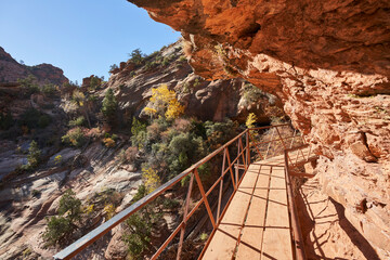 A boardwalk wraps around a steep rock overhang as the trail continues to canyon overlook. It is a...