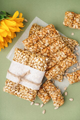 Sunflower with tasty kozinaki and seeds on green background