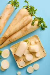 Plate with fresh daikon radishes on blue background
