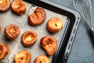 Baking tray with tasty Yorkshire pudding on blue background