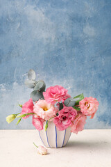 Vase with beautiful pink eustoma flowers on white table