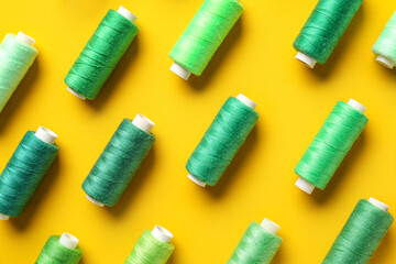 Composition with colorful thread spools on yellow background