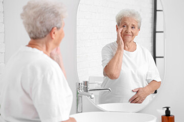 Senior woman looking in mirror at home