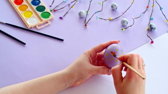 Woman hand painting easter egg with watercolors, preparation for egg hunt game. Happy easter congratulation symbol