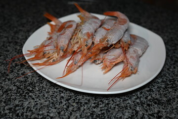red frozen king prawns on a white plate 