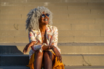 Afro-american lady with grey afro hair relaxing in the sun in city