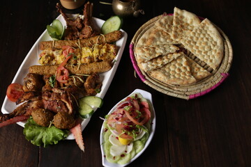 Chicken kebab plater served in tray salad bowl, naan texture background restaurant style selective...
