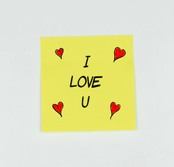 Yellow Post-it with the phrase I love u written in black, with a white background and red hearts