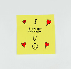 Yellow Post-it with the phrase I love u written in black, with a white background, red hearts and a smiley face