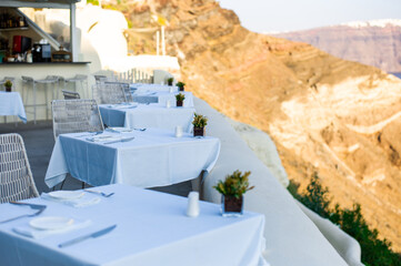 Tables on the caldera cliff of a Santorini hotel with great aegean sea view greece