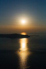 Naklejka premium Quietly sunset at Santorini with a boat in the sunlight reflected in the water of aegean sea greece