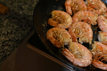 fried white-footed prawn hovstas close-up, browned cooked king prawns in a frying pan 