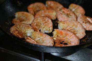 fried white-footed prawn hovstas close-up, browned cooked king prawns in a frying pan 