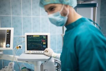 Male surgeon keeping track of vital functions of the body during cardiac surgery. Doctor checking...