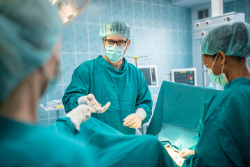 Confident male surgeon taking surgical scissors from assistant in operating theatre. Medical...