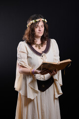 Portrait of a beautiful woman dressed in medieval clothing, reading an antique book.