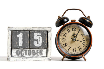 October 15 on wooden calendar with alarm clock white background.