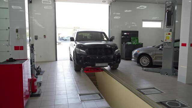 Vehicle enters auto workshop for check-up. Modern garage, car inspection, owner drives, shop tools ready. Professional maintenance, diagnostics in bright, updated service center. SUV approach