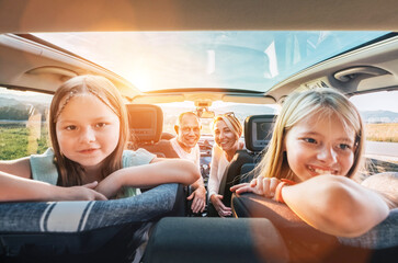 Young couple with daughters portrait sitting in a modern car with a transparent roof. Happy family...