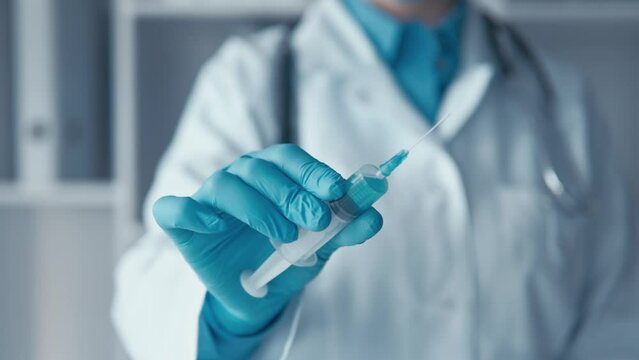 The doctor holds a syringe in his hand, brings it to the camera. The laboratory manufactures a syringe for further medical research, striving to reach new heights in the treatment of diseases.