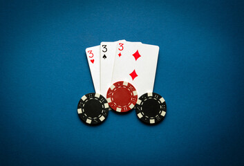 Poker game with three of a kind or set combination. Chips and cards on the blue table in poker club