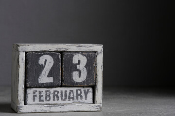 February 23 on wooden calendar, on dark gray background.