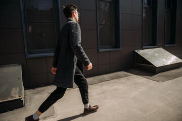 A person walking outside. The person is wearing trousers, a coat, and foo