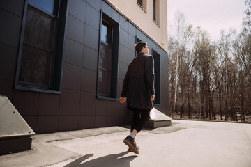 A person walking outside a building. The person is wearing a coat and wa