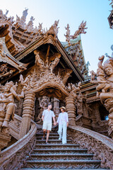 A diverse multiethnic couple of men and women visit The Sanctuary of Truth wooden temple in Pattaya Thailand