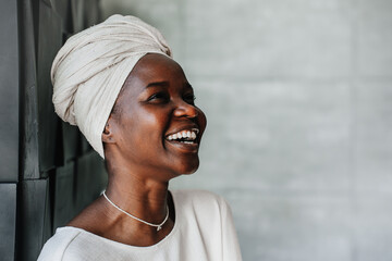 Joyful African woman in a headscarf laughing heartily. Happy Brazilian girl in turban laughing.