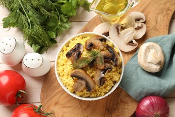Obraz na płótnie Canvas Tasty millet porridge, mushrooms and dill in bowl on light wooden table, flat lay