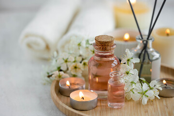 Obraz na płótnie Canvas Aromatherapy, home decor concept. Glass perfume bottle, elegant composition with spring flowers. Burning candles, spa setting, essential oils, organic pure aromatic ingredients, atmosphere of relax