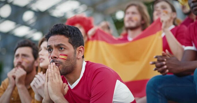 Close camera shot of people worrying about their favourite sports team. Supporting Spanish national team. Spanish flags painted on peoples faces. Cheering after successful outcome in game.