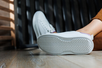 White leather sneakers on women's legs. Women's legs in comfortable casual sneakers