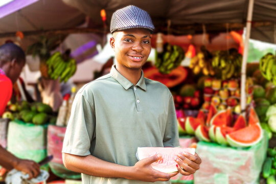 side view of happy young trader holding a watermelon in local market
