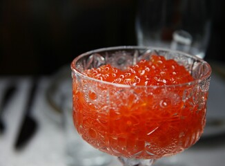 Red salmon caviar in a transparent vase close up photo 