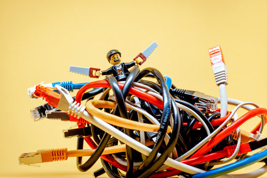 IT guy fighting a bundle of tangled wires. Information Technology concept. Illustrative editorial