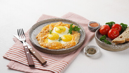 Fried eggs with cheese and sesame served on plate over napkin, vegetarian breakfast
