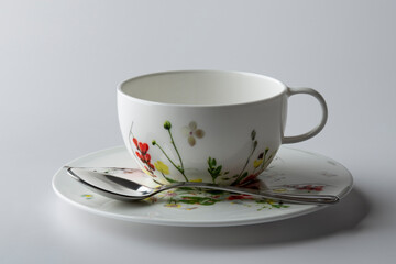 Teacup decorated with painted flowers with plate and teaspoon
