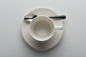 Top view of white coffee cup with saucer and teaspoon