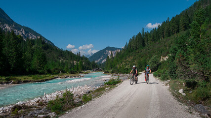 Two men mountainbiking along the turquoise river Isar in the Karwendel mountains during sunny blue sky day in summer, Tyrol Austria. - 704096130