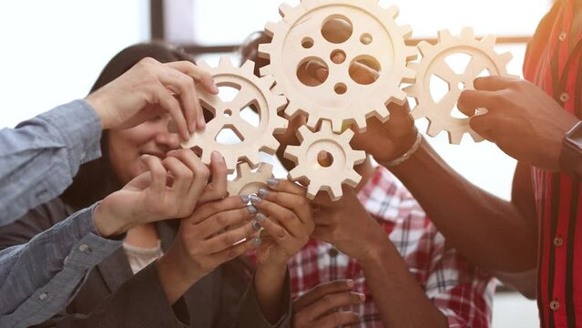 Office worker holding cog wheel as unity and teamwork in corporate workplace concept.