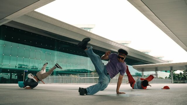 Group of diverse hipster or street dancer doing head spin in front of mall. Happy energetic break dancer practice b-boy step dancing with friends. Outdoor sport 2024. Street dancer concept. Sprightly.