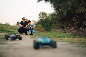 A son and father playing with remote controlled toy cars on a dirt road