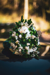 Obraz na płótnie Canvas White and green wedding bouquet placed on a car. 