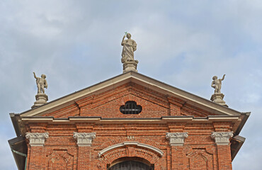 Tympanum on the gable of the church of San Maurizio and Santa Margherita against clouded sky in Monza, Lombardy, Italy