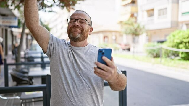 Eureka! cheerful middle-aged caucasian man with beard, firstly celebrating using smartphone on outdoor city street, texting a winning message!