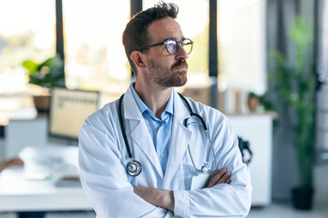 Fototapeta premium Mature male doctor with stethoscope over neck working while looking forwards in the medical consultation.