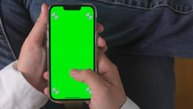 Close-up of hands holding smartphone with green screen for app presentations