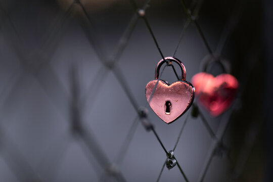 A red padlock hanging on a bridge fence as a sign of love and romance.
